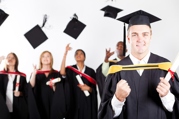 young male graduate at graduation with classmates