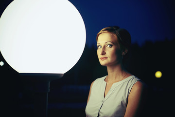 young woman in the night sky near the street lamp
