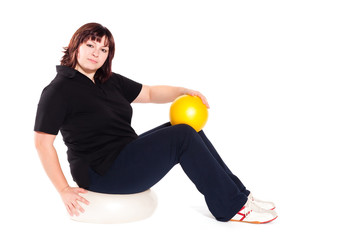 Fototapeta na wymiar Shot of a overweight young woman exercise on fitness ball agains