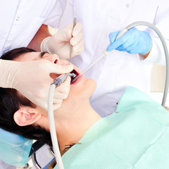 A dentist and a nurse curing young man`s teeth