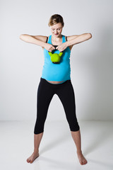 Fototapeta na wymiar Pregnant woman exercising with kettlebell