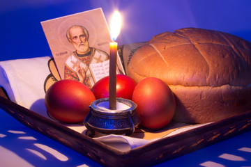Easter eggs and kulich, a candle, the icon on a wooden tray