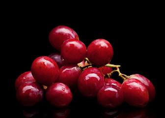 bunch of red grapes on a black background with water drops