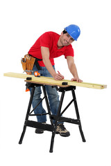 Man marking a measurement on a wooden plank