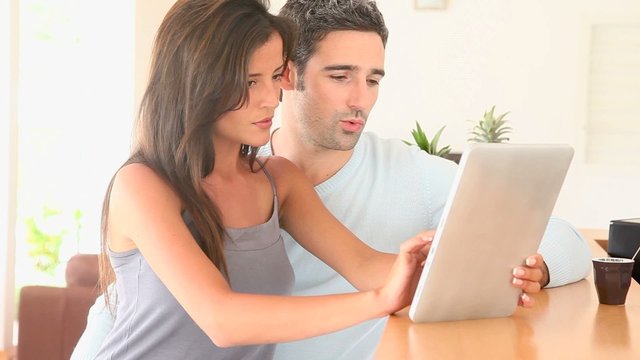 Couple at home websurfing on internet with tablet