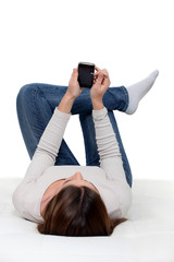 A woman lying and checking her phone.