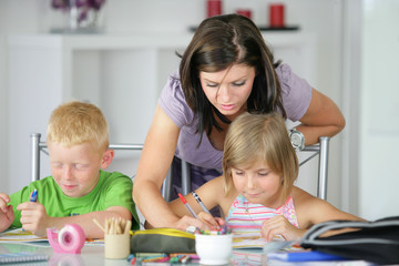 Obraz na płótnie Canvas Matka pomaga jej dzieci z pracy domowej