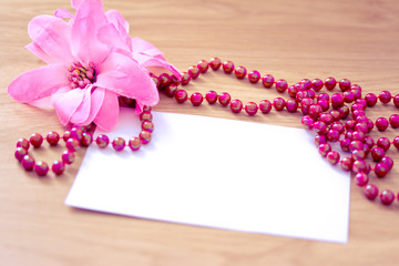 Fototapeta na wymiar red zroszony naszyjnik i różowy kwiat z pustej karty