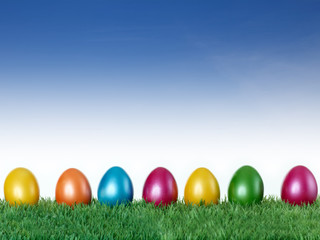 Fototapeta na wymiar Wesołych Świąt! Kolorowe jaja na łąki z błękitne niebo