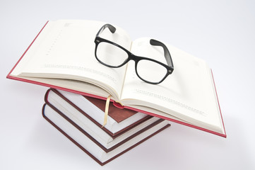 Stack of books with opened notebook and glasses