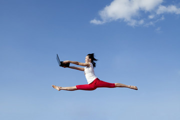 Beautiful woman jumps with laptop