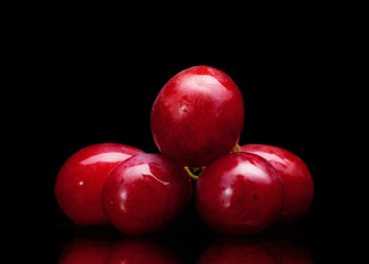 bunch of red grapes on a black background with water drops