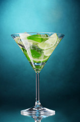 glass of cocktail with lime and mint on blue background
