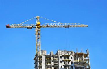 Building crane and building under construction against blue sky