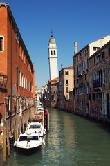 Fototapeta na wymiar Canal with a leaning bell tower in Venice.