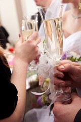 wedding decorated glasses in hands of groom and bride