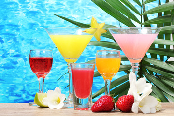 exotic cocktails and flowers on table on blue sea background