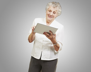 portrait of senior woman touching digital tablet over grey backg