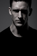 Man in black t-shirt posing on gray background.