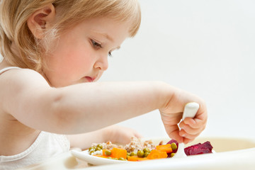 Adorable baby girl eating fresh vegetables