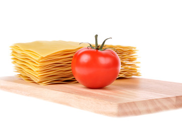 Lasagna pasta with tomato on cutting board isolated on white bac