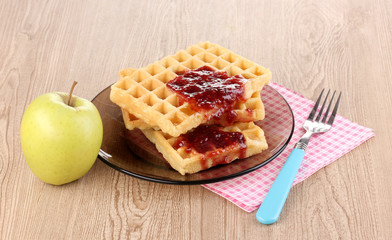 Tasty waffles with jam on plate on wooden background