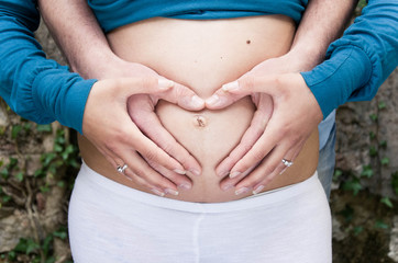 Pregnant Caucasian Woman and Man Making Heart With Hands