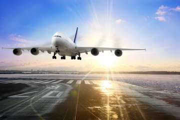 Obraz premium Pasażerski samolot lądujący na pasie startowym na lotnisku. Wieczór