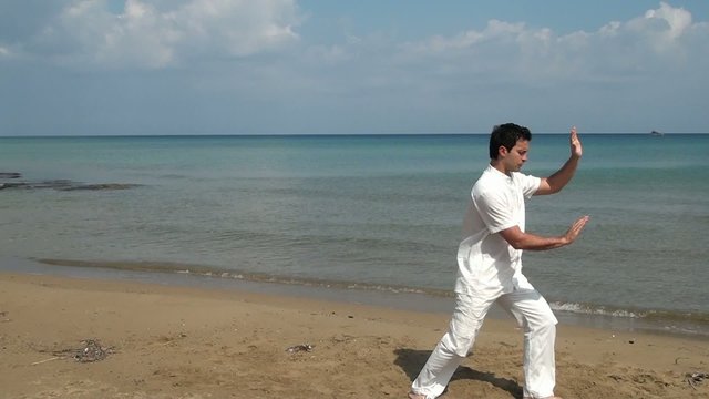 Man practicing Tai Chion the beach