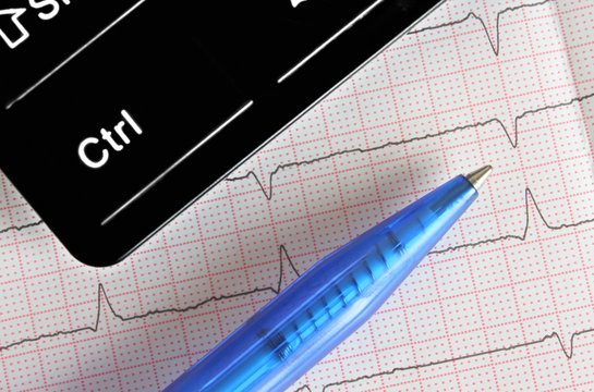 Pen, fragment of the keyboard on the background of ECG
