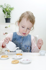 Cute little girl drinks tea with bagels