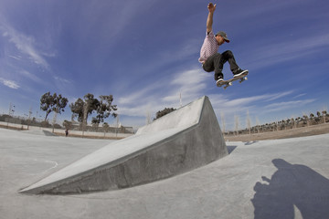 joven realizando un salto con el monopatin rampa