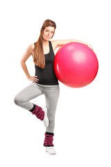 Full length portrait of a smiling female holding a fitness ball