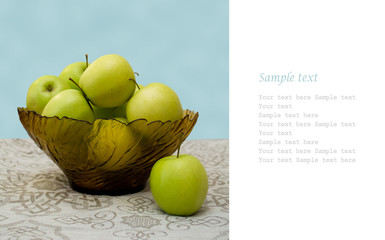 green apples in a glass vase on the table cloth