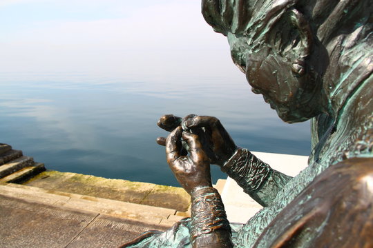 Bronze statue of a seamstress working with a thread