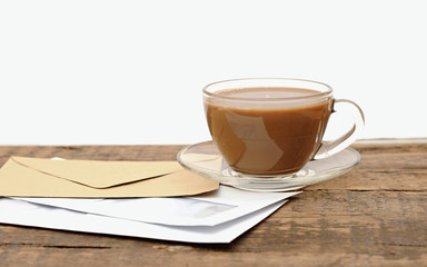 blank envelopes and a glass coffee cup on a wooden desk