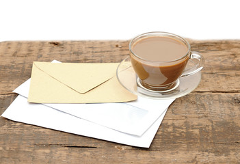 blank envelopes and a glass coffee cup on a wooden desk