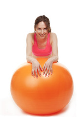 junge frau stützt sich auf orangenem fitness ball