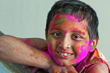 Close up face of young boy playing Holi, smiling with colors on