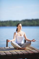 Fototapeta na wymiar beautiful young girl training yoga near a lake