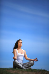 Naklejka na ściany i meble beautiful young girl training yoga near a lake