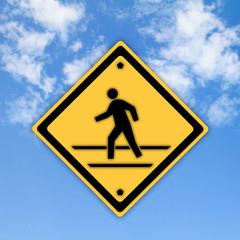 Crosswalk sign with a man walking on yellow with a blue sky back