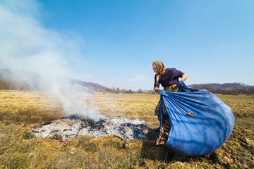 Senior rural woman burning fallen leaves