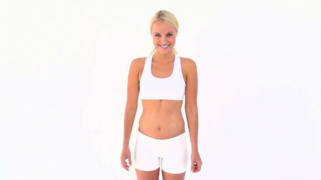Blonde shrugging her shoulders after touching her skinny belly