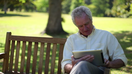 Retired man using an ebook - Powered by Adobe