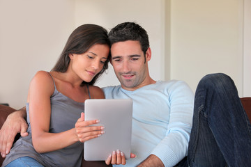 Couple sitting in sofa with electronic tablet