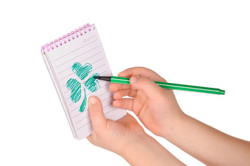 children's hands hold notebook with a painted clover