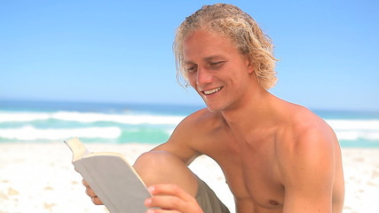 Smiling blonde man reading a novel - Powered by Adobe