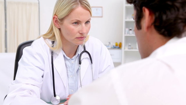 Serious doctor touching the shoulder of her patient