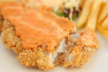 fried breaded fish steak with gravy topping and one peice sliced